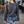 Person wearing a dark gray sweatshirt with a colorful pocket design and a blue patterned skirt in an outdoor setting.